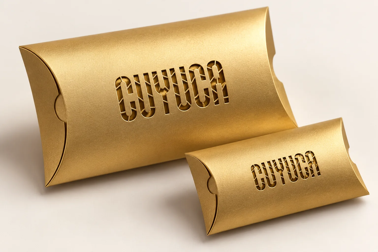 Gold Cuyuca pillow-box packaging with cut-out stencil lettering.