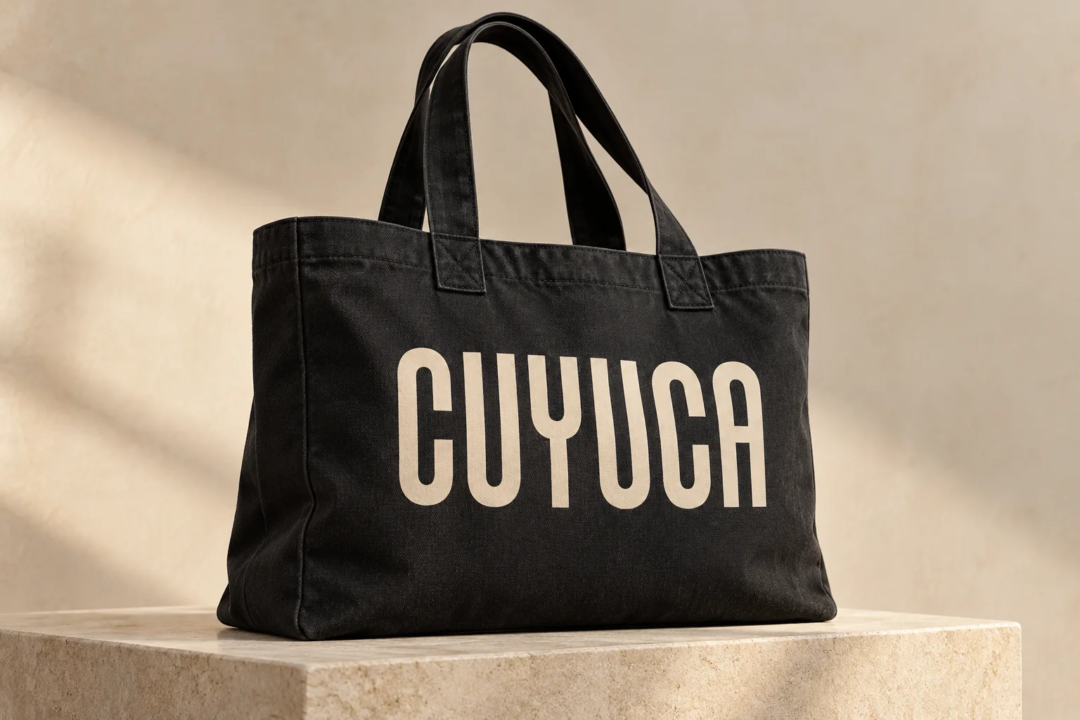 Black canvas tote printed with the solid Cuyuca wordmark.