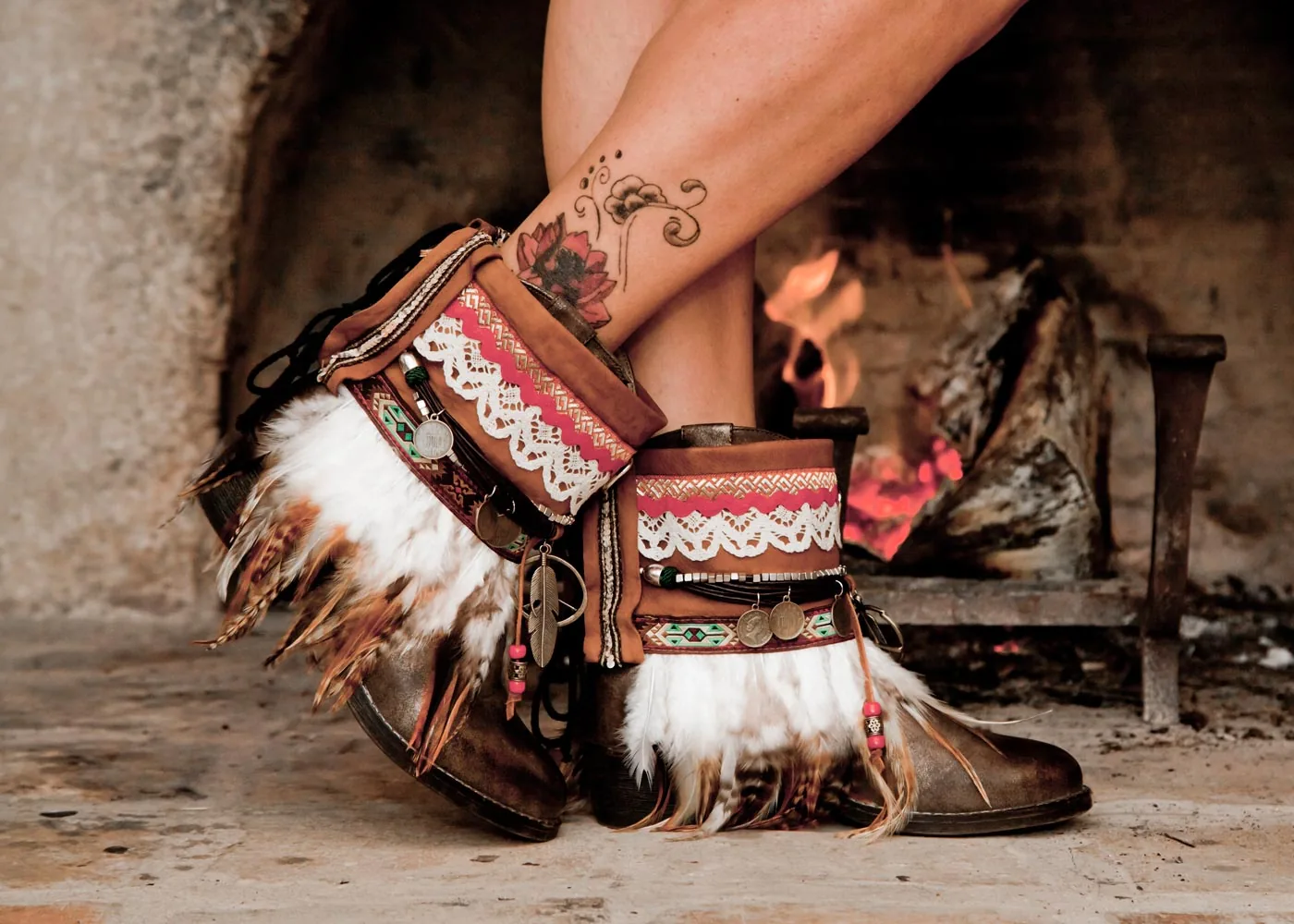 Original Cuyuca home-page photograph showing feathered boot accessories beside a fireplace.