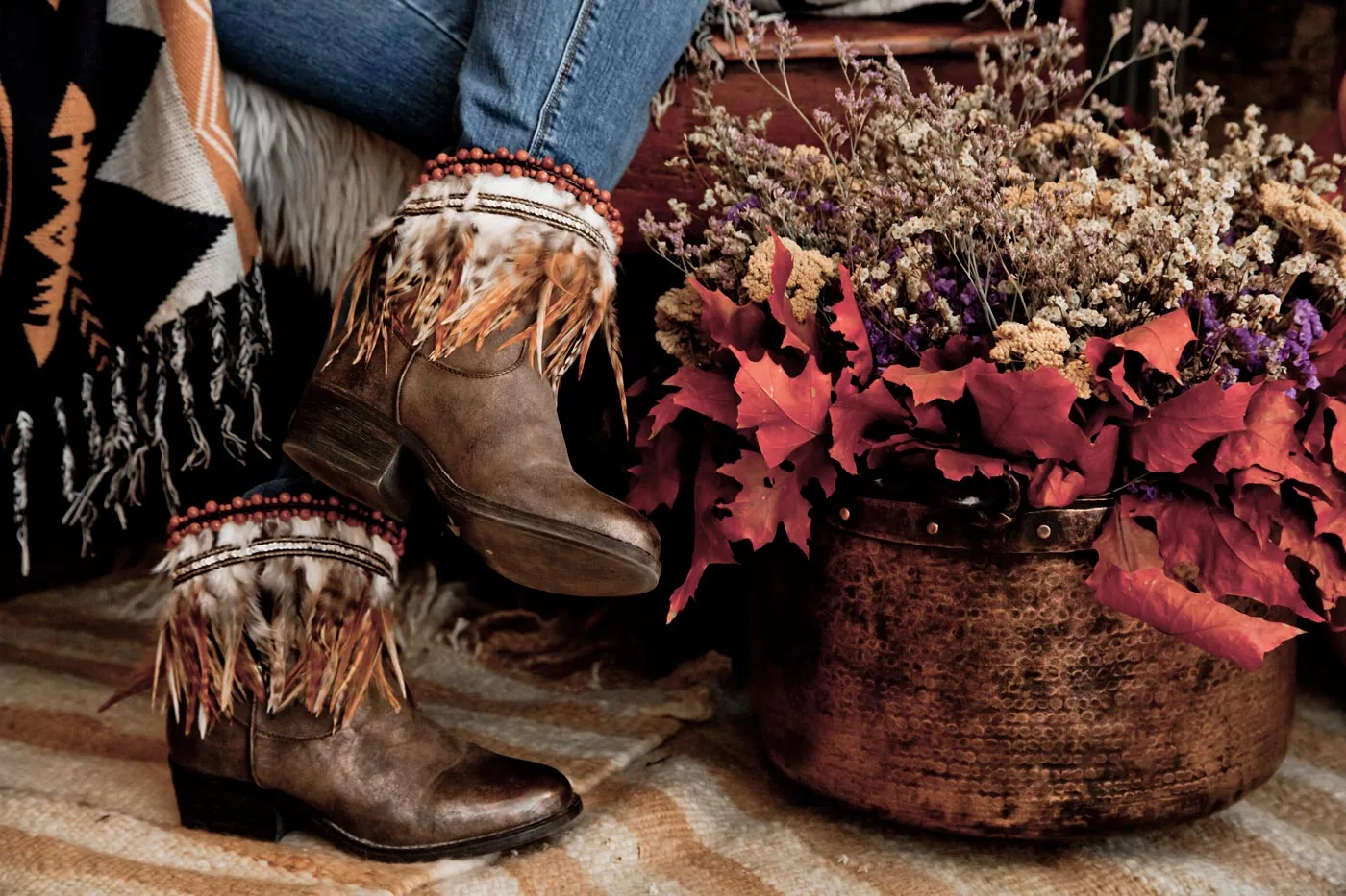 Original Cuyuca web image with feathered boot accessories, autumn leaves and dried flowers.