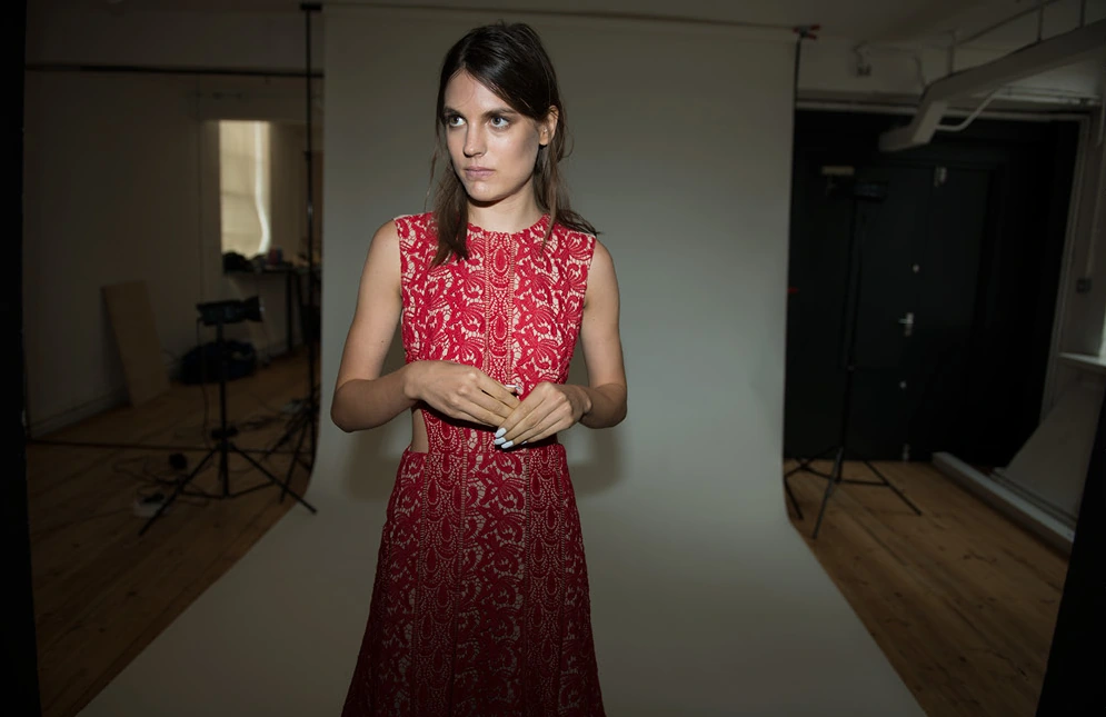 The same red lace dress worn by the model backstage, without overlaid copy.